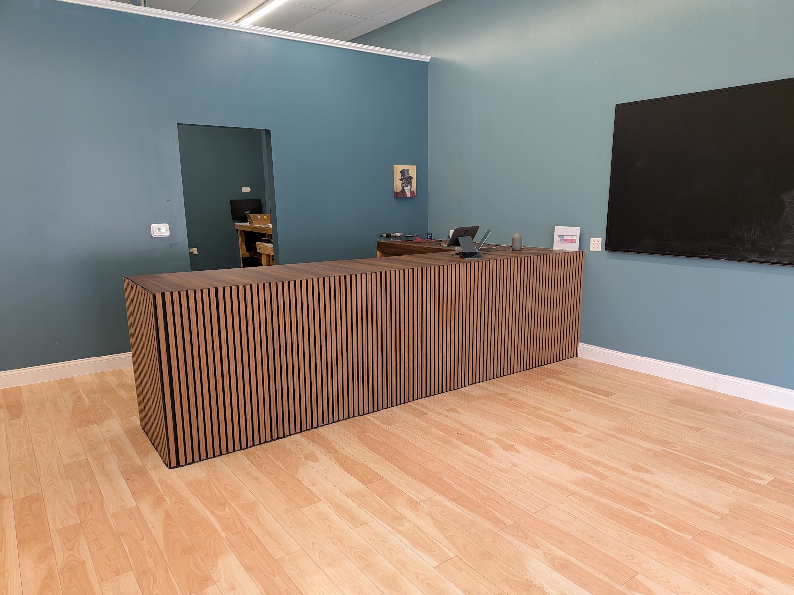 Counter close-up: L-shaped wooden slatted reception desk with laptop